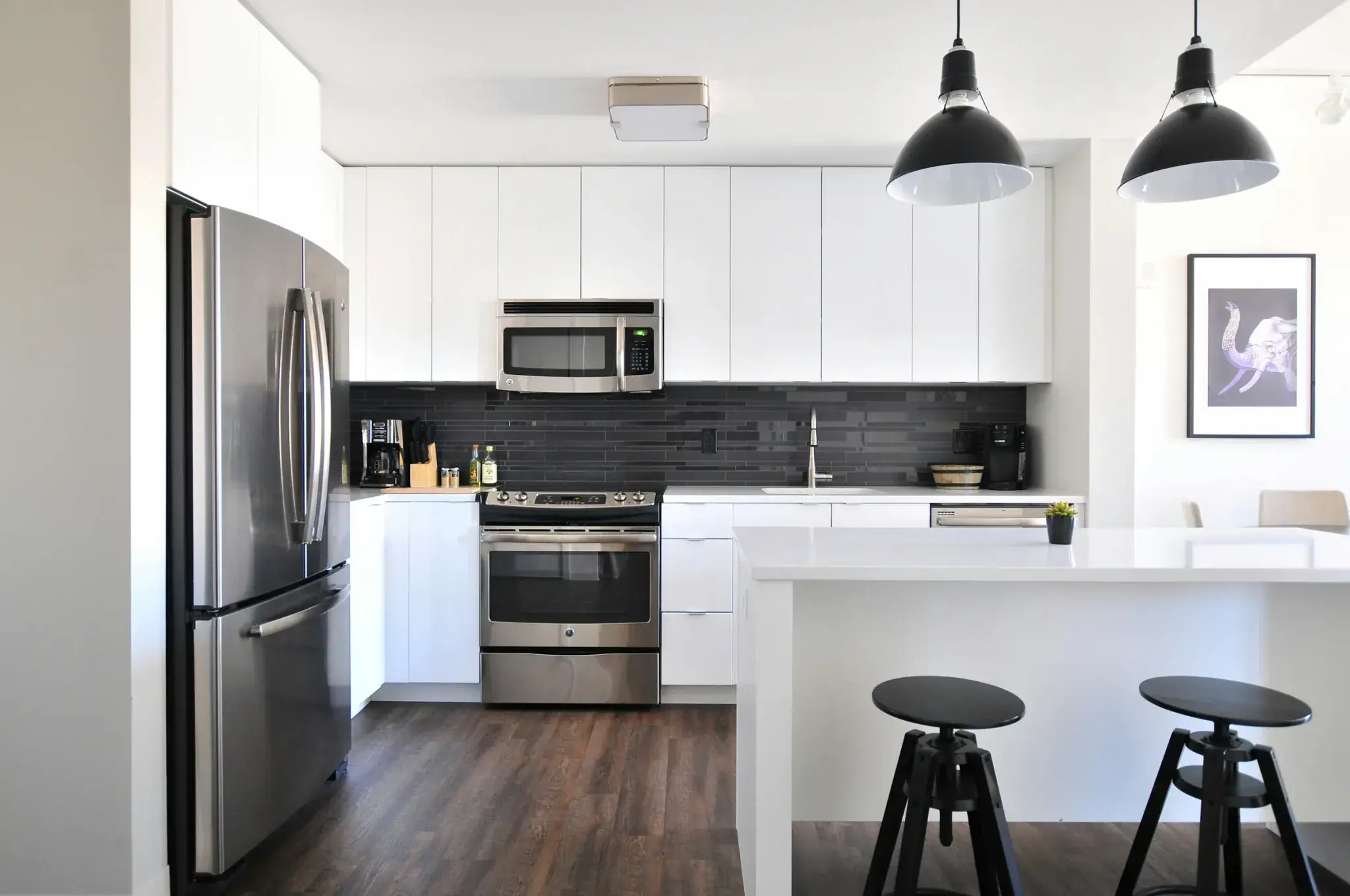A built-in microwave above a cooker in a kitchen with a black tiled splashback